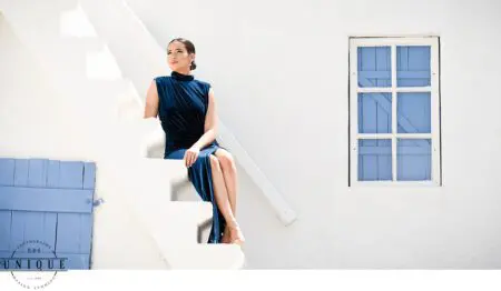Woman in blue dress sits on white steps.