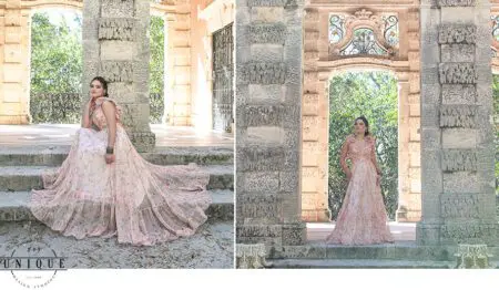 Woman in pink floral dress poses in stone archway.