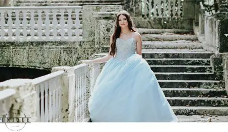 Young woman in a blue gown on stone steps.