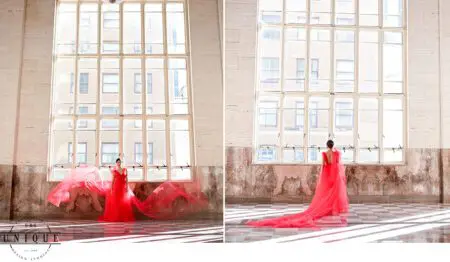Woman in red dress by large windows.