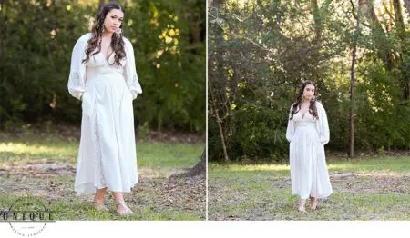 Woman in white dress standing in woods.