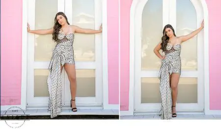 Woman in white dress poses by pink wall.