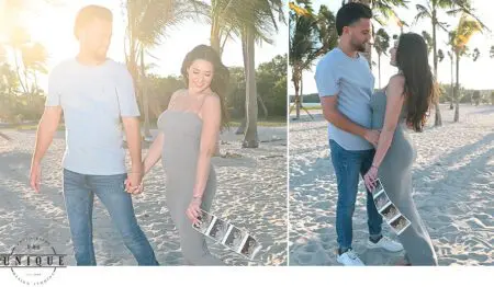 Couple holding ultrasound photos on beach.