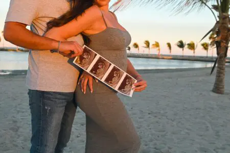 Couple holding ultrasound on beach.