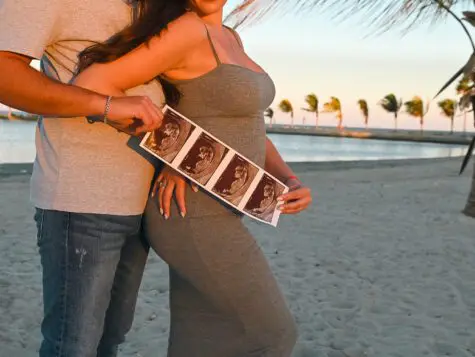 Couple holding ultrasound on beach.