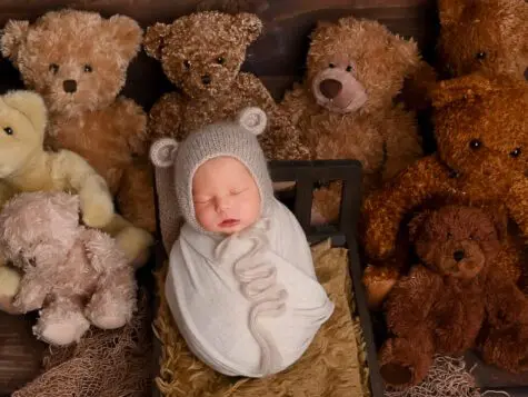 Sleeping baby surrounded by teddy bears.