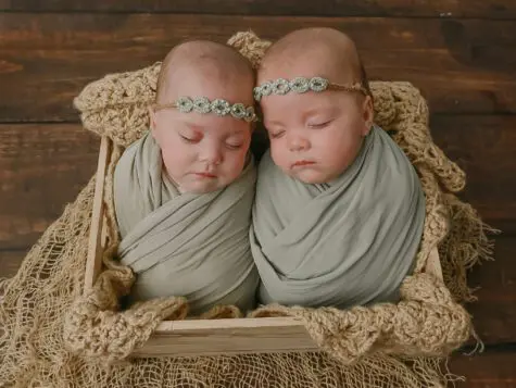 Twin babies sleeping in a wooden box.