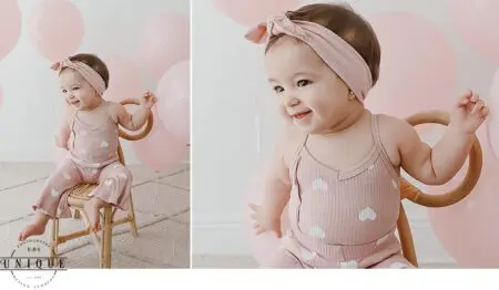 Baby girl in pink heart romper and headband.
