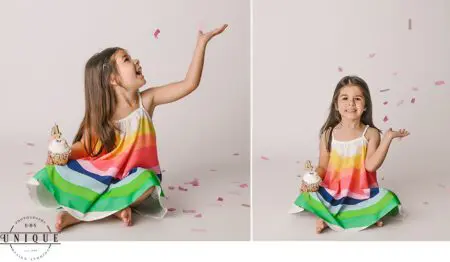 Girl in rainbow dress celebrating with confetti.
