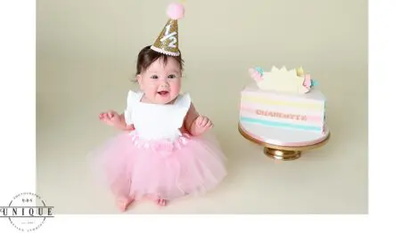 Baby girl in pink tutu with birthday cake.