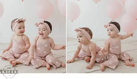 Twin babies in pink heart print outfits.