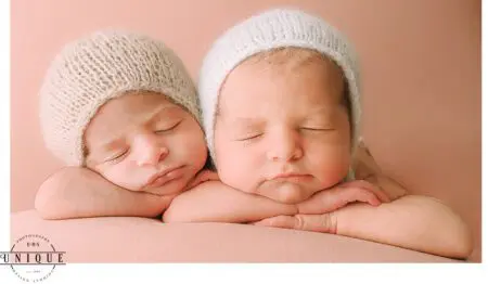 Twin babies sleeping in knitted hats.