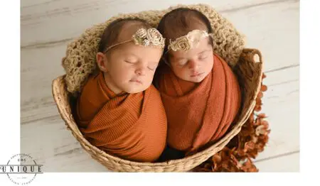 Twin babies sleeping in a basket.