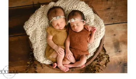 Twin newborn babies sleeping in a basket.