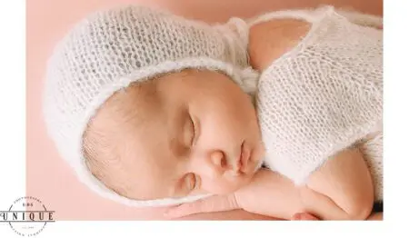 Sleeping newborn baby in white knitted hat.