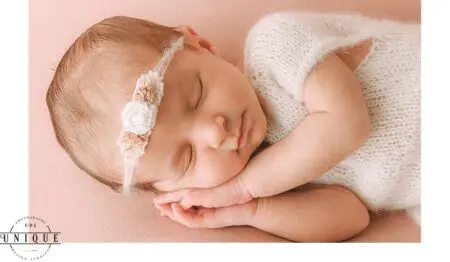 Sleeping newborn baby girl with flower headband.