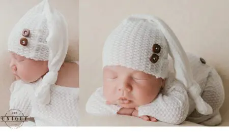 Sleeping newborn baby wearing white outfit and hat.