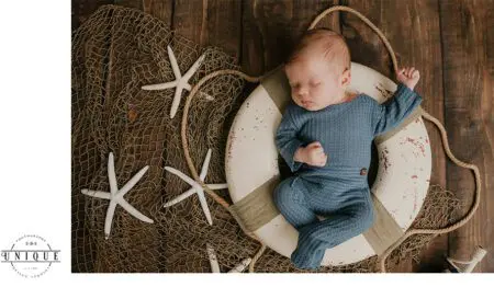 Sleeping baby in a life preserver on wood floor.