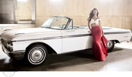 Woman in red dress by vintage car.