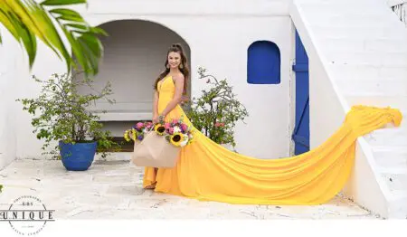 Woman in yellow dress holding sunflowers.