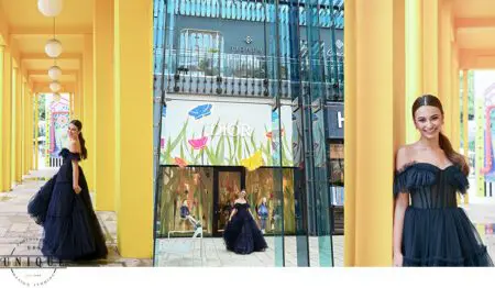 Woman in a black dress poses in a yellow walkway.