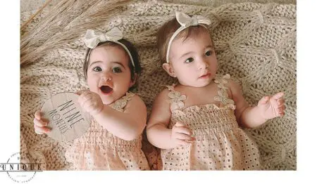 Twin babies in matching dresses at nine months old.