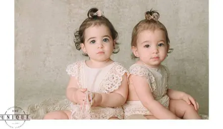 Two baby girls in lace dresses.