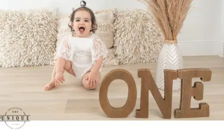Baby girl in white dress celebrating her first birthday.
