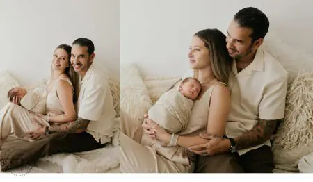 Parents cuddling newborn baby on couch.