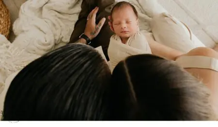 Parents cradling a sleeping newborn.