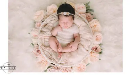 Newborn baby sleeping in a basket of roses.