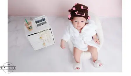 Baby girl in a robe and curlers.
