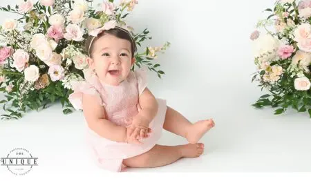 Smiling baby girl in pink dress with flowers.