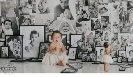 Two babies in front of framed photos.