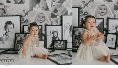 A baby girl in a white dress surrounded by pictures.