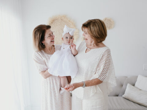 Two grandmothers holding a baby girl.