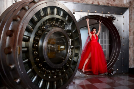 Woman in red dress by a vault door.