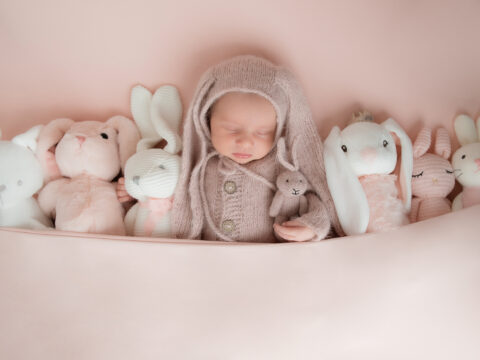 Sleeping baby with bunny plush toys.