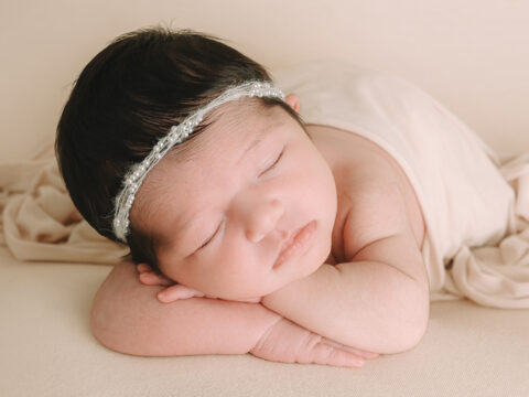 Sleeping newborn baby with pearl headband.